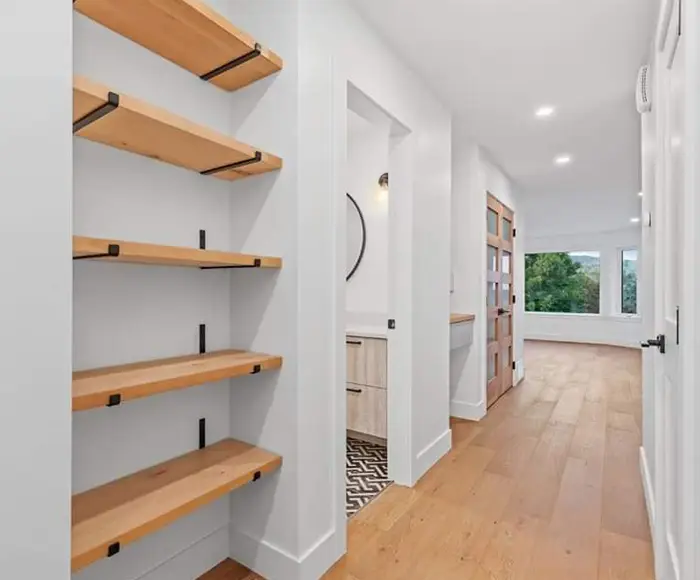 Modern hallway with custom floating wood shelves and hardwood flooring